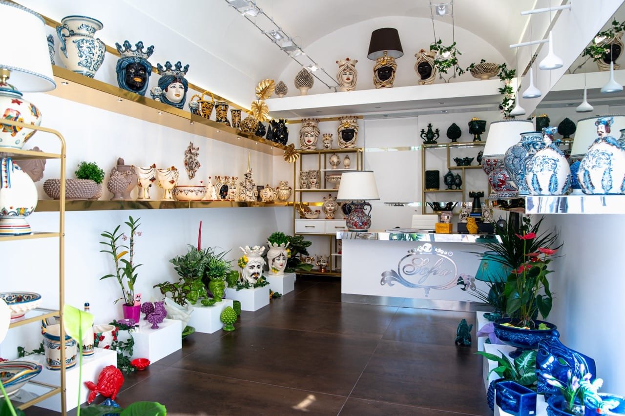 Sofia Ceramiche showroom with Testa di Moro heads, vases and lamps on white and gold shelves