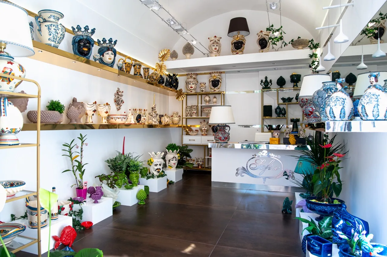 Sofia Ceramiche showroom with Testa di Moro heads, vases and lamps on white and gold shelves
