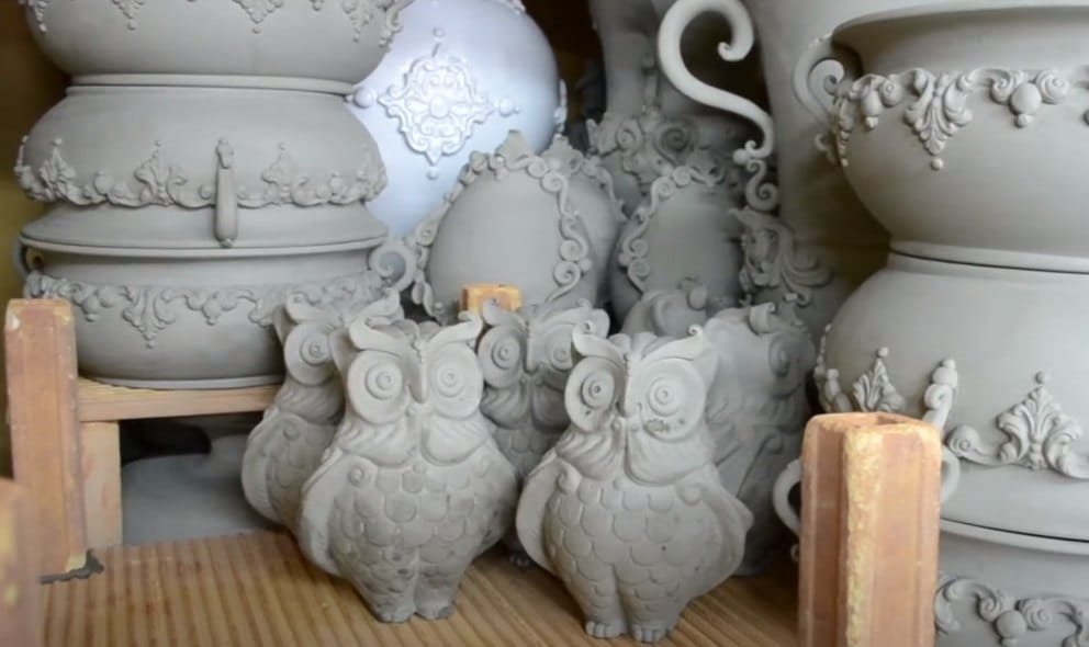 Unglazed biscuit pieces, owls and relief vases, on the workshop shelves