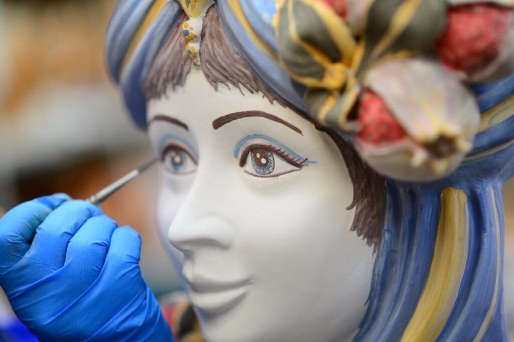 Painting the eye of a ceramic head with a fine brush